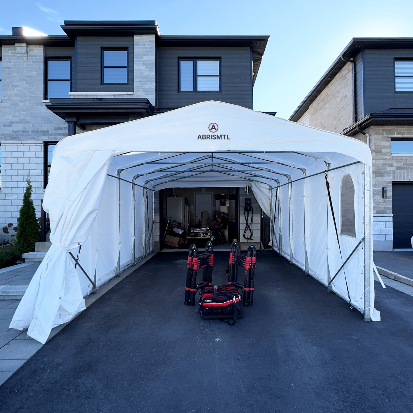 White ABRIS MTL Carport or Car Shelter set up in a driveway with equipments underneath underneath.